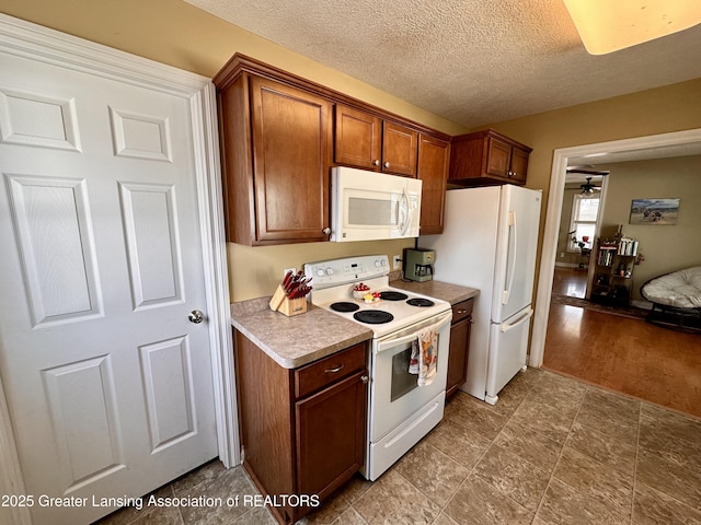 kitchen with white appliances, brown cabinetry, ceiling fan, light countertops, and a textured ceiling