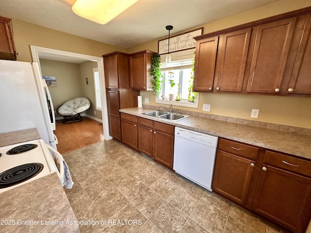 kitchen featuring brown cabinets, white appliances, pendant lighting, and a sink