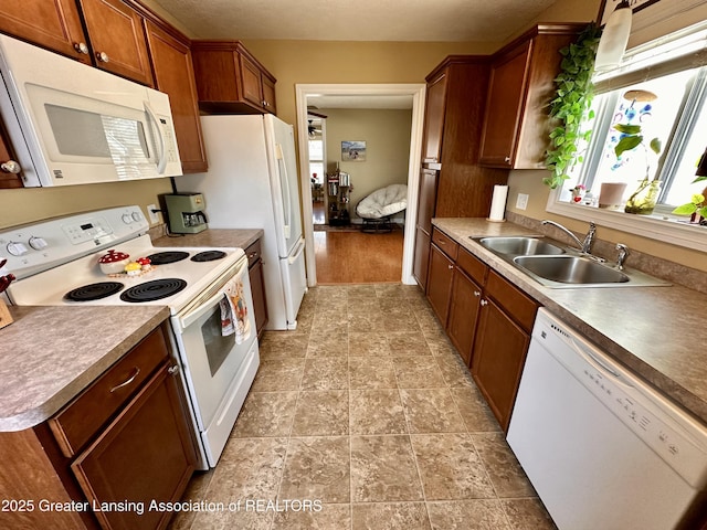 kitchen featuring white appliances, brown cabinets, and a sink