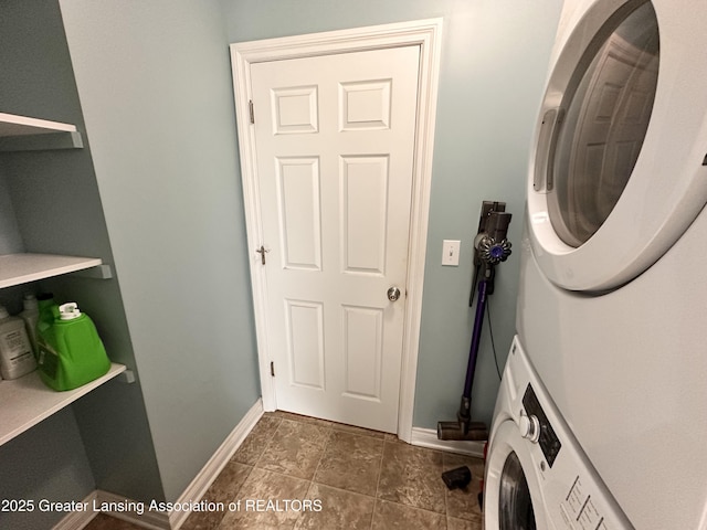 clothes washing area featuring baseboards, laundry area, and stacked washer / dryer