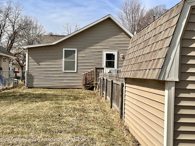 view of side of property featuring fence and roof with shingles