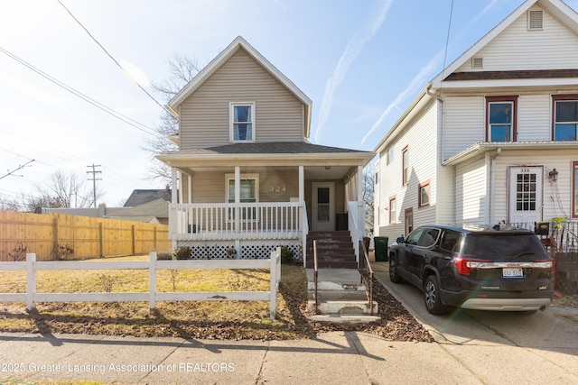 view of front of property featuring a porch, a fenced front yard, and a shingled roof