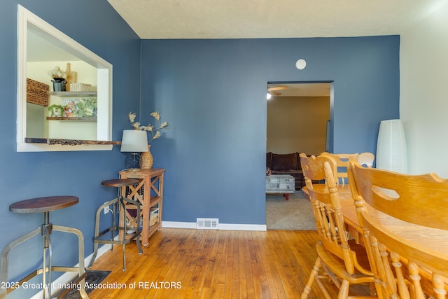 dining room featuring visible vents, ceiling fan, baseboards, and hardwood / wood-style flooring