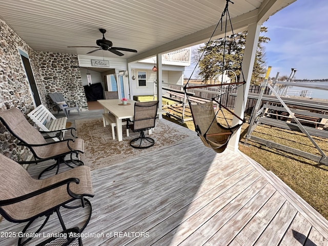 1793 N Shore Dr, Crystal, MI 48818 - deck with outdoor dining area, a water view, and a ceiling fan