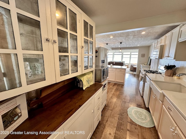 1793 N Shore Dr, Crystal, MI 48818 - kitchen with stainless steel appliances, glass insert cabinets, white cabinetry, open floor plan, and hardwood / wood-style floors