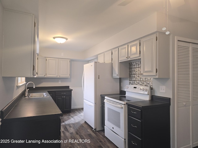 kitchen featuring white appliances, dark wood-style floors, a sink, white cabinets, and dark countertops