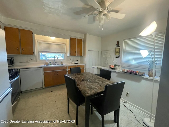 kitchen with ceiling fan, a sink, light countertops, appliances with stainless steel finishes, and brown cabinets