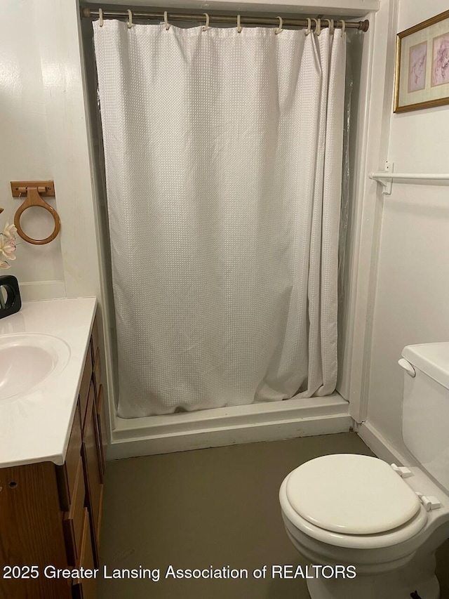 bathroom featuring toilet, a stall shower, and vanity