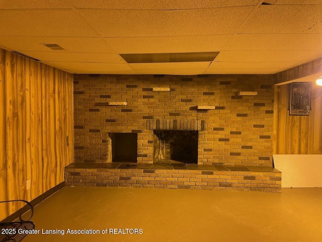 finished basement featuring a fireplace, a paneled ceiling, visible vents, and wood walls