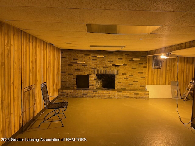 finished basement featuring a drop ceiling, wooden walls, and brick wall