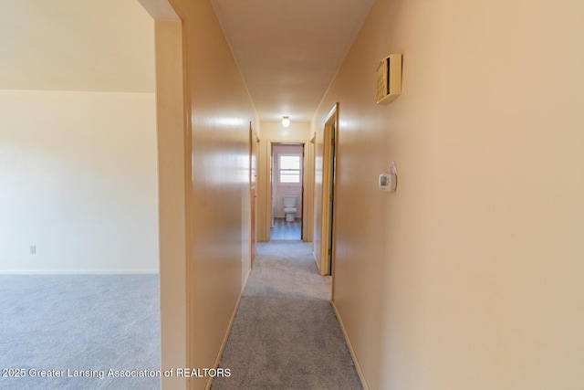 hall featuring carpet flooring and baseboards