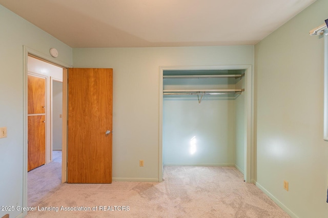 unfurnished bedroom featuring a closet, baseboards, and carpet flooring