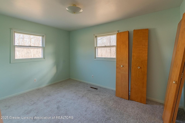 unfurnished bedroom with carpet flooring, baseboards, and visible vents