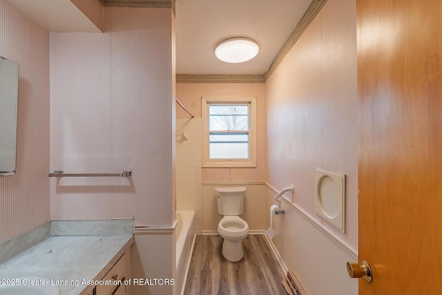 full bathroom with toilet, wood finished floors, vanity, crown molding, and shower / bathtub combination