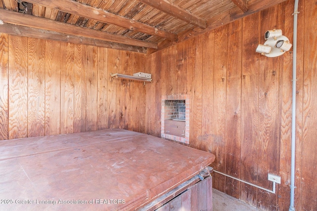 unfurnished room with beamed ceiling, wood walls, and wooden ceiling