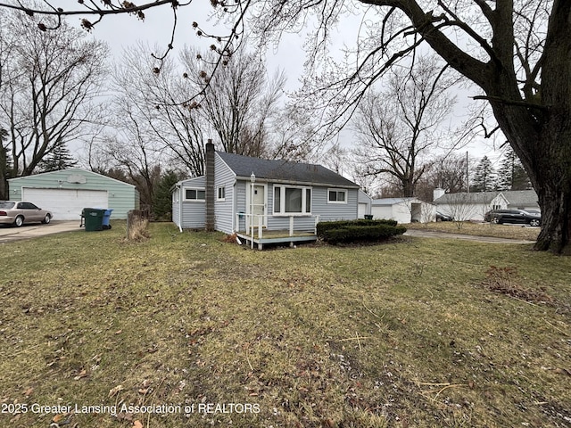 bungalow with an outbuilding, a garage, a front yard, and a chimney