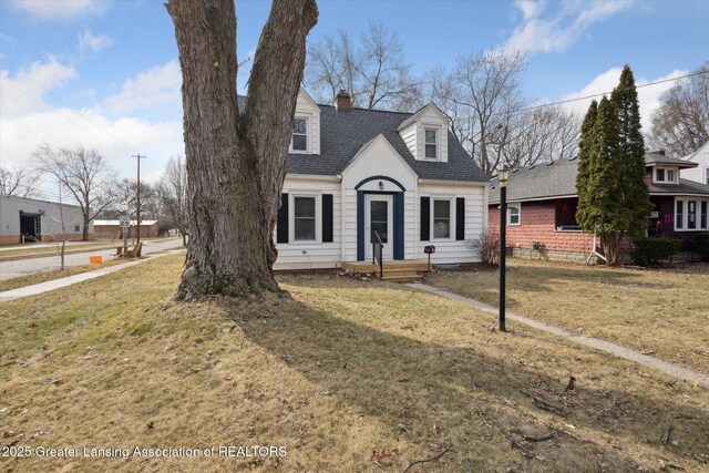 cape cod-style house with a chimney, a front lawn, and a shingled roof