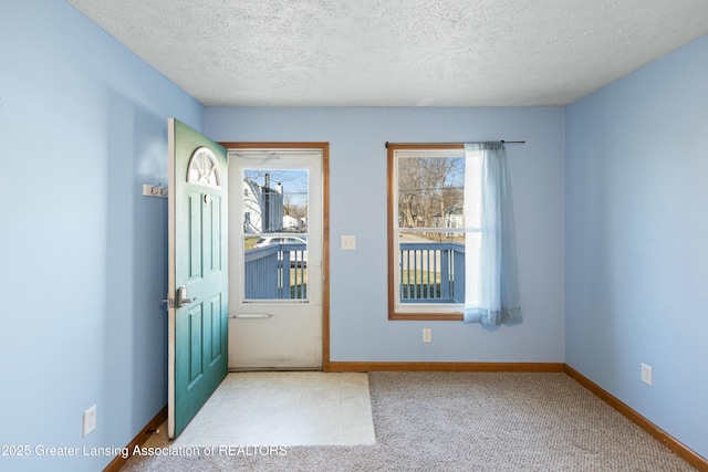 foyer with baseboards, a textured ceiling, and a healthy amount of sunlight