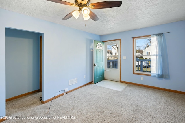 carpeted spare room featuring visible vents, baseboards, ceiling fan, and a textured ceiling