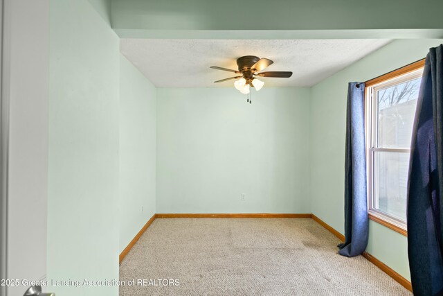 carpeted spare room with baseboards, ceiling fan, and a textured ceiling