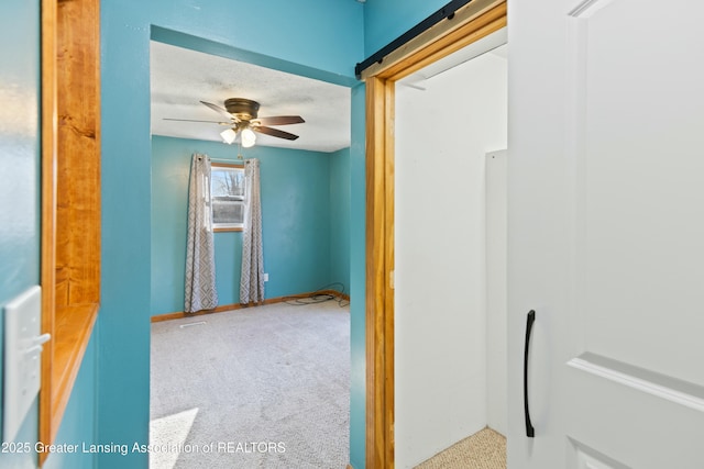 hall featuring baseboards, carpet, and a textured ceiling