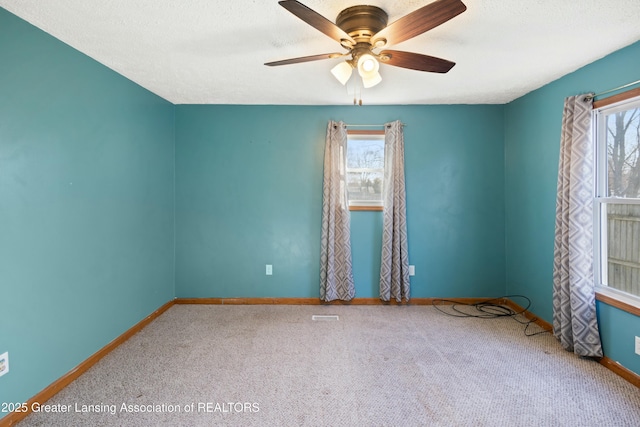 carpeted empty room with baseboards, ceiling fan, and a textured ceiling