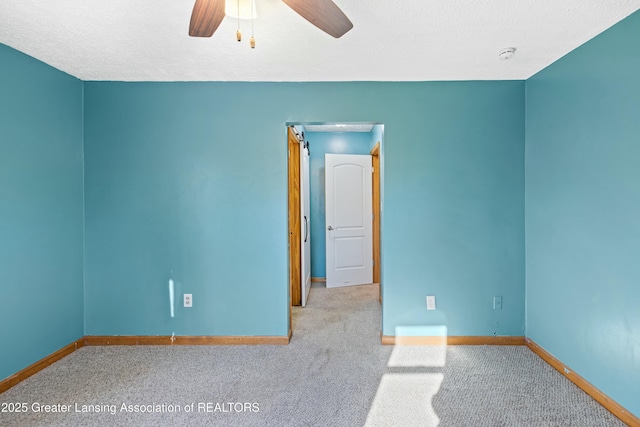 carpeted spare room featuring baseboards, a textured ceiling, and a ceiling fan