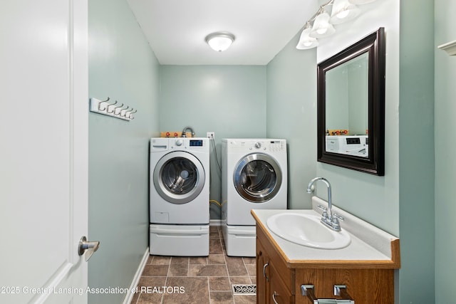 laundry room featuring independent washer and dryer, stone finish floor, baseboards, a sink, and laundry area