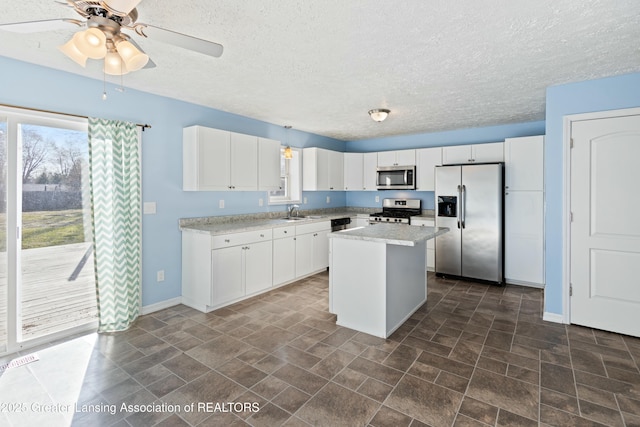 kitchen with white cabinetry, a center island, a sink, ceiling fan, and appliances with stainless steel finishes