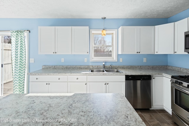kitchen featuring white cabinetry, a textured ceiling, a sink, pendant lighting, and appliances with stainless steel finishes