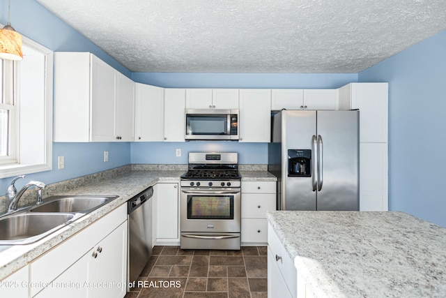 kitchen with white cabinetry, a sink, stainless steel appliances, and a textured ceiling
