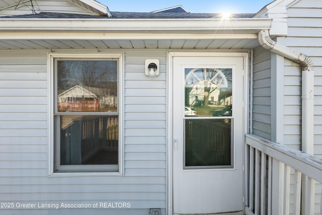 entrance to property featuring roof with shingles
