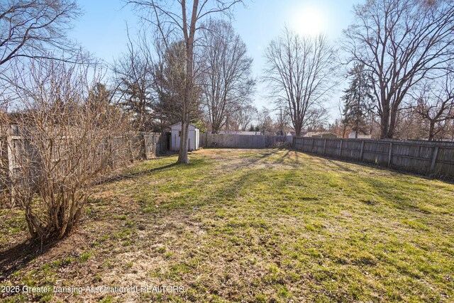 view of yard featuring an outdoor structure, a fenced backyard, and a storage unit