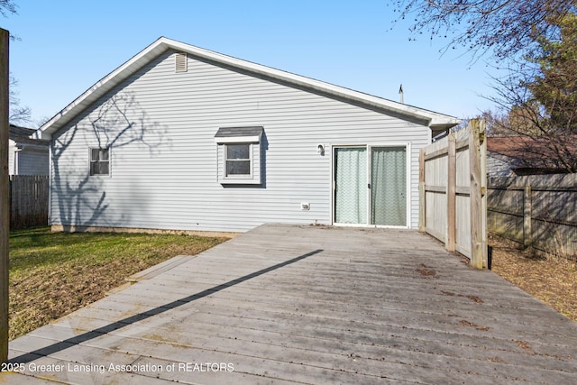 rear view of house with fence and a deck