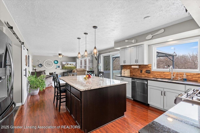 13305 Nelson, Bath, MI 48808 - kitchen with dark stone counters, a barn door, appliances with stainless steel finishes, a sink, and open floor plan