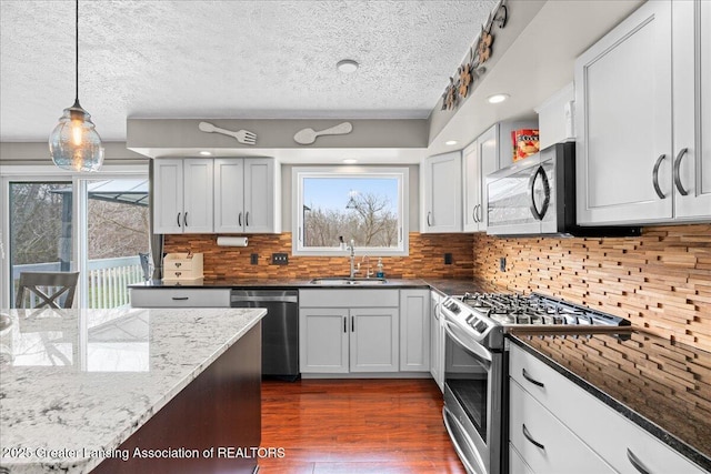 13305 Nelson, Bath, MI 48808 - kitchen featuring dark stone countertops, a sink, dark wood-style flooring, appliances with stainless steel finishes, and backsplash