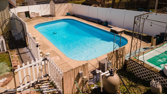 view of pool with an outbuilding, a shed, a fenced backyard, a patio, and a fenced in pool