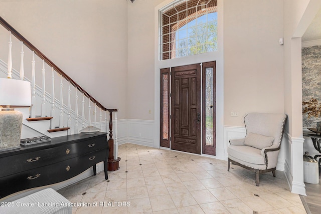 13600 Forest Hill Rd, Grand Ledge, MI 48837 - entryway featuring a wainscoted wall, stairs, a towering ceiling, and a decorative wall