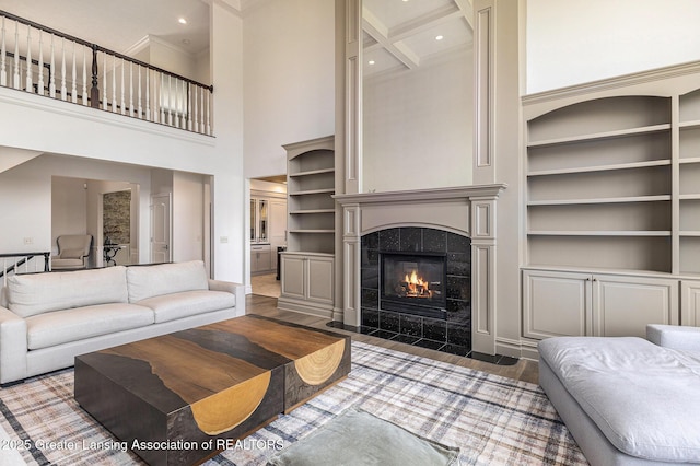 13600 Forest Hill Rd, Grand Ledge, MI 48837 - living room featuring a high ceiling, built in features, baseboards, a tile fireplace, and ornamental molding