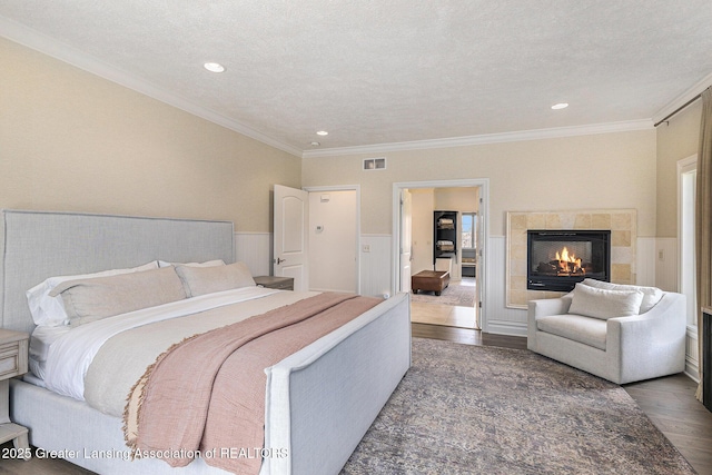 13600 Forest Hill Rd, Grand Ledge, MI 48837 - bedroom featuring wood finished floors, wainscoting, a tile fireplace, ornamental molding, and recessed lighting