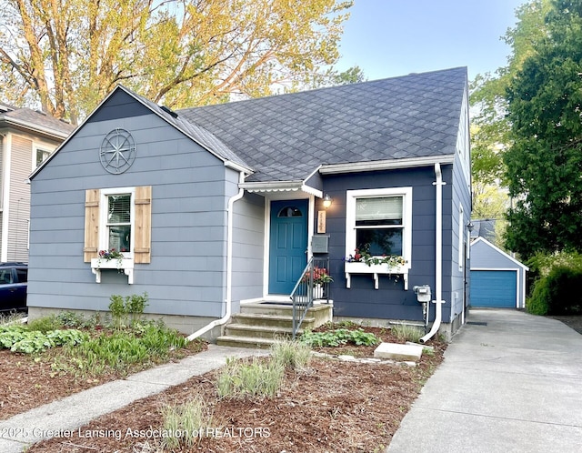909 Britten Ave, Lansing, MI 48910 - view of front facade with a shingled roof, a detached garage, and an outbuilding