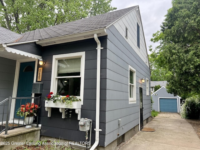 909 Britten Ave, Lansing, MI 48910 - view of home's exterior with concrete driveway, an outdoor structure, a garage, and a shingled roof
