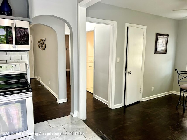 909 Britten Ave, Lansing, MI 48910 - hallway featuring arched walkways, wood finished floors, and baseboards