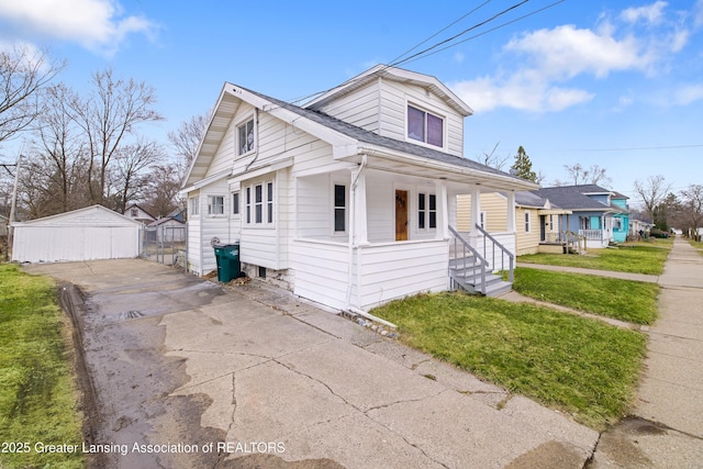 bungalow with driveway, a front yard, an outdoor structure, and roof with shingles