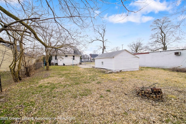 view of yard featuring an outbuilding, a fenced backyard, and a fire pit