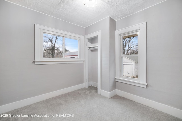 unfurnished bedroom featuring a closet, carpet, baseboards, and a textured ceiling