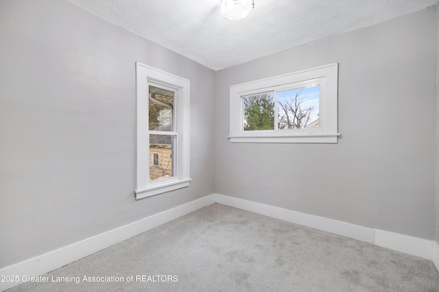 spare room with baseboards, carpet, and a textured ceiling