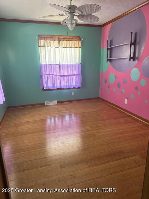 464 N Rolland Rd, Weidman, MI 48893 - empty room featuring a textured ceiling, visible vents, crown molding, ceiling fan, and wood finished floors