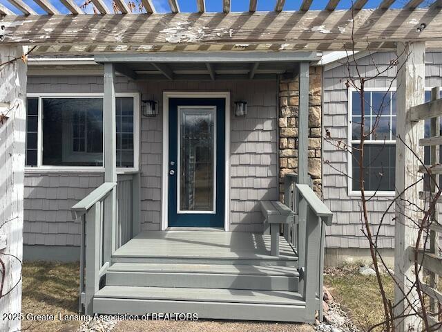 464 N Rolland Rd, Weidman, MI 48893 - doorway to property with stone siding and a pergola