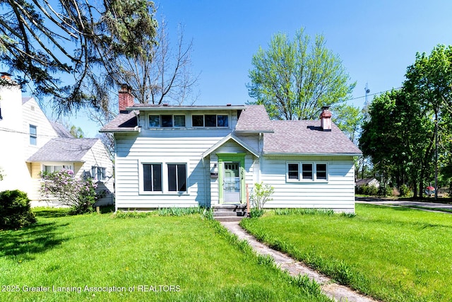 bungalow-style house featuring a chimney, a front lawn, and a shingled roof